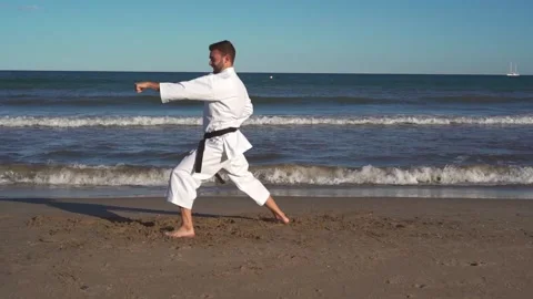 Karate fighter practicing katas on the beach at sunset. Karate fighter practi Stock Footage 146605016