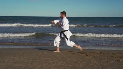 Karate fighter practicing katas on the beach at sunset. Karate fighter practi Stock Footage 146605019