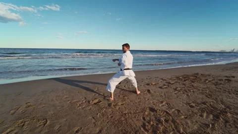 Karate fighter practicing katas on the seashore at sunset. Karate fighter pra Stock Footage 146604973