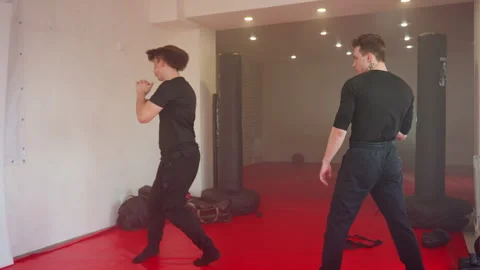 Karate practitioners jumping on red mats in gym during martial arts training Stock Footage 325965167