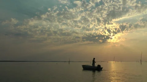Kariba Sunset man standing up in small boat fishing Stock Footage 53008554