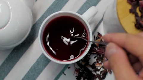 Karkade tea is stirred with a spoon in slow motion Stock Footage 156258960