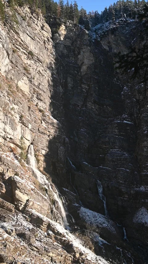 A karst spring in the middle of a huge rock wall in the mountains, first snow, v Stock-Footage 260873358