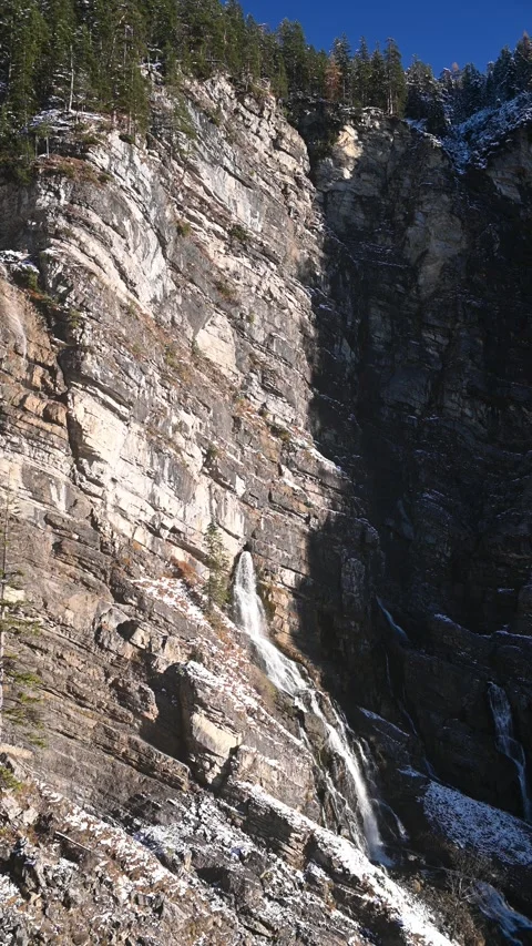 A karst spring in the middle of a huge rock wall in the mountains, first snow, v Video stock 260873514