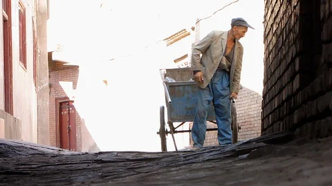 Kashgar, man pulling hand cart in cobbled alleyway towards low angle POV Vidéo 129460564