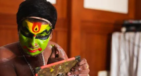 Katakhali dance performer doing face paint and makeup in front of hand held m Stock Photos