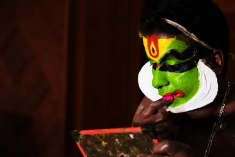 Katakhali dance performer doing face paint and makeup in front of hand held m Stock Photos