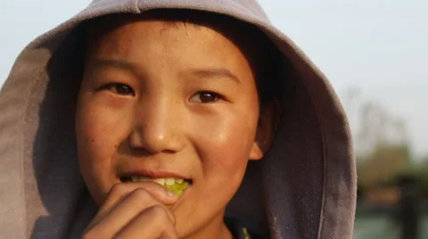Kathmandu Nepal boy chewing on fruit and posing for camera at childrens home in Видео 45209176