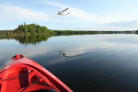 A kayak on a lake with a floatplane taking off Stock Photos