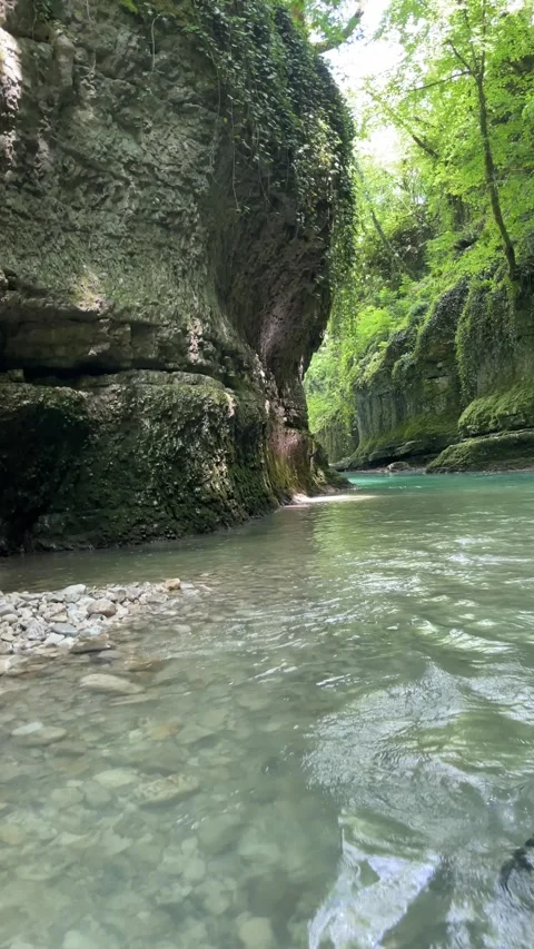A kayak moves through clear turquoise water between towering mossy limeston.. Vídeo Stock 340025677
