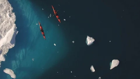 kayak paddler beneath icebergs in Greenland