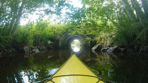 Kayak paddling into culvert pipe under road Stock Footage 117722941