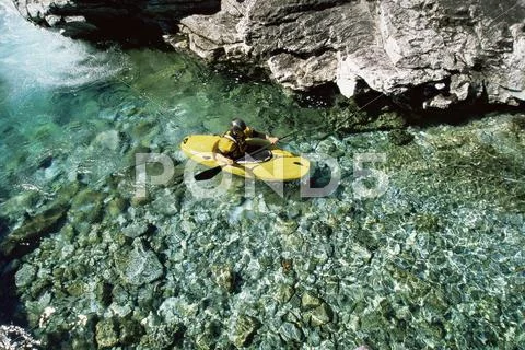 Kayaker in calm water near large rocks Stock Photos