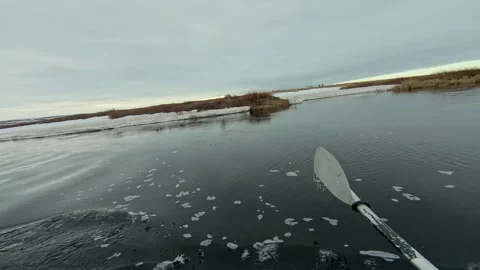A kayaker floats down a cold river in the Arctic, surrounded by ice floes and a Video stock 278699002