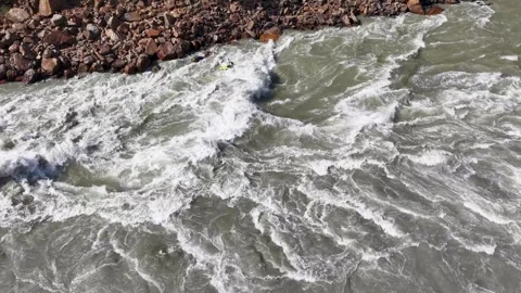Kayaker navigating rough river rapids in aerial shot above rushing Видео 347763279