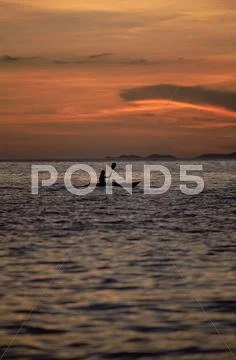 Kayaker outdoors in ocean at sunset (far away/silhouette) Stock-Fotos