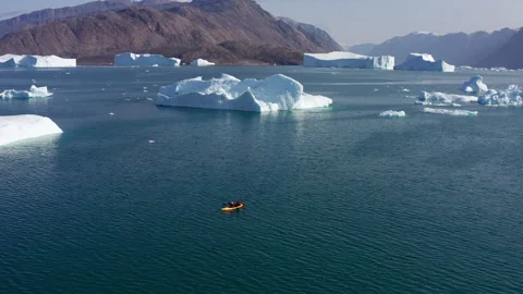 Kayaker Paddling Through Cold Blue Arctic Waters Surrounded By Massive Icebergs Video stock 346572998