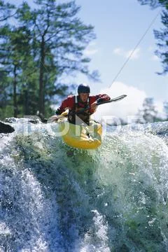 Kayaker in rapids coming over waterfall (selective focus) Stock Photos