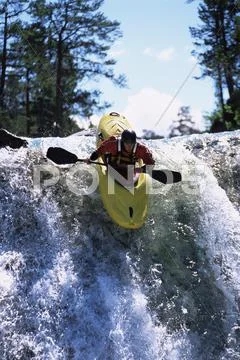 Kayaker in rapids going over waterfall (selective focus) Stock Photos