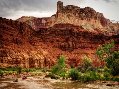 Kayaker on Small Creek Beneath Large Desert Rock Buttress Stock Photos