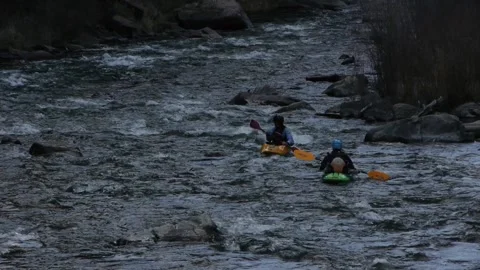 Kayakers headed downstream on a river, choppy water Stock Footage