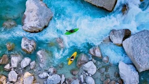 Kayakers navigate rapids between large rocks in a river Foto stock
