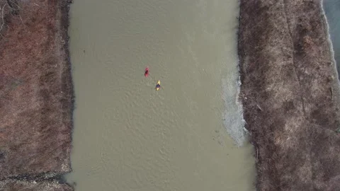 Kayakers paddle downstream on a muddy river Stock Footage 142178170