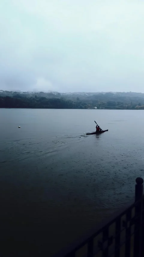 Kayakers paddling on a lake under clouds and heavy rain. Sport in bad weather Stock Footage 318729532