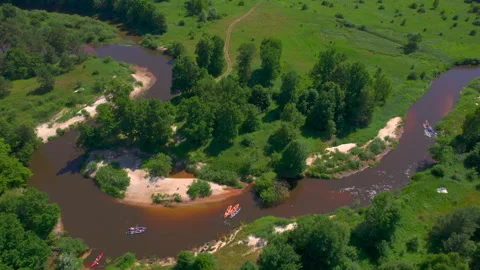 Kayakers spread across sweeping river curves around green wooded island 库存影片 341006088