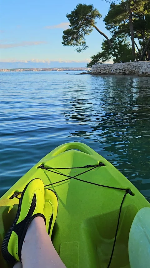 Kayaking along green pine coast in calm blue sea with audio. Stock Footage 340242313