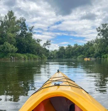 Kayaking on calm river under cloudy sky: exploring nature's beauty Stock Photos