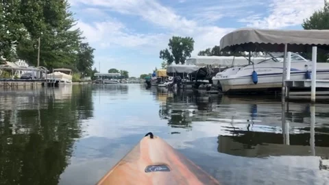 Kayaking down a canal lined with boats Stock Footage 160132347