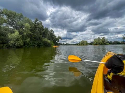 Kayaking on a lake with dramatic cloudy sky and lush green trees Stock Photos
