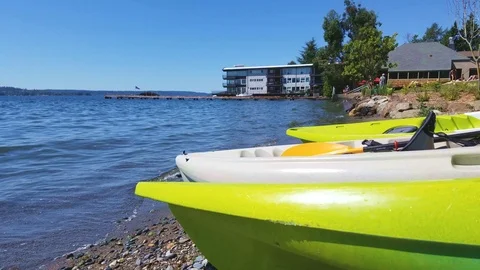 Kayaks in closeup laying by the summer seashore, people sunbathing Stock Footage