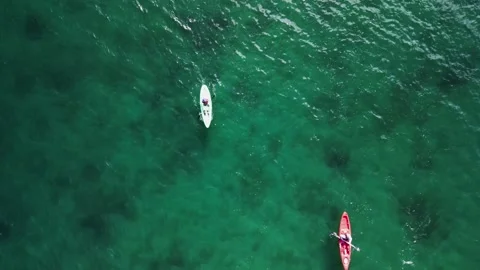Kayaks of different colors float on the water in the ocean Stock Footage 253082639