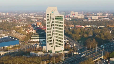 Kbc tower angular facade green windows rise above highways low buildings tree Vídeos de archivo 329086224
