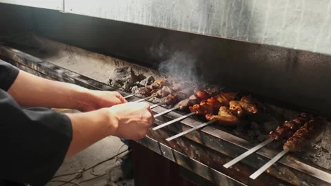 A kebab maker turns over kebabs of chicken, meat, liver and vegetables fried on Stock Footage 254694648