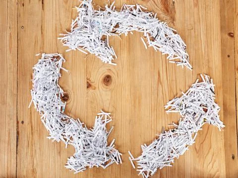 Keep the cycle going. Studio shot of shredded paper forming a recycling logo. Stock Photos