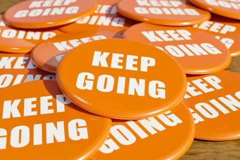 Keep going. Keep going. Orange badges laying on the table with the message... Stock Photos