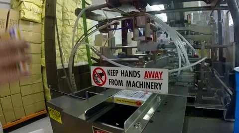 Keep hands away sign on a large automated card making machine assembly line Stock Footage 40064740