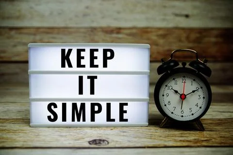 Keep it Simple text on LED lightbox with alarm clock on wooden background, .. Stock Photos