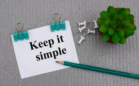 KEEP IT SIMPLE - words on a white sheet with clips on a gray background with Stock Photos