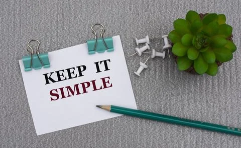 KEEP IT SIMPLE - words on a white sheet with clips on a gray background with Stock Photos