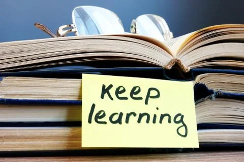 Keep learning. Open book and glasses on the table. Stock Photos