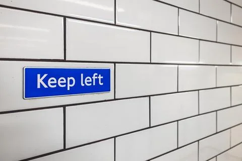 Keep Left sign on white tiled wall inside London Underground station Stock Photos