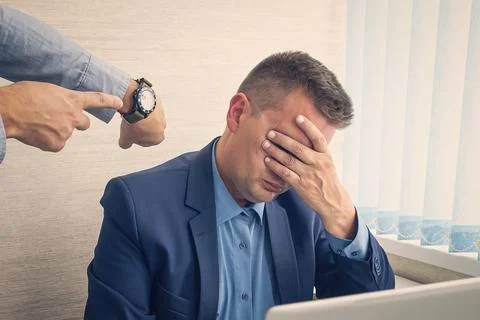 Keep track of time. man point at clock. being late at work. The boss scolds the Stock Photos