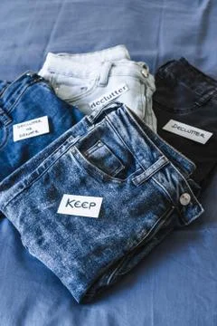 Keep vs Declutter label on different jeans in various denim colors, tidying u Stock Photos