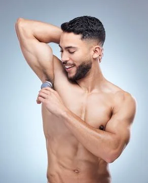 Keeping his underarm skin dry. Shot of a young man applying deodorant against a Stock Photos