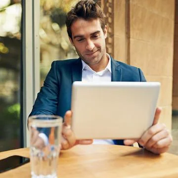 Keeping up with the latest business developments. A young businessman using his Stock Photos