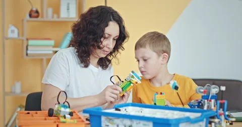 Keeping in mind. Smiling boy sitting with her teacher at the school desk looking Stock Footage 171780795